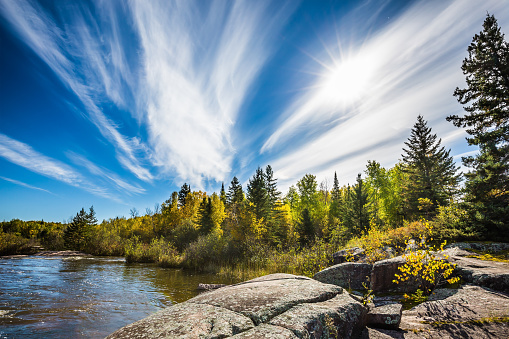 Incredible cirrus clouds  and huge flat stones in Old Pinawa Dam Park. Indian summer in Manitoba, Canada. The concept of ecological and recreational tourism