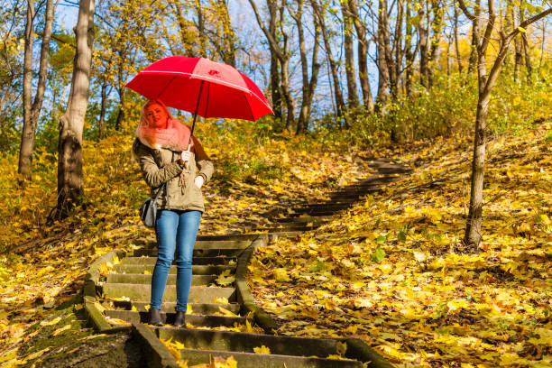 istock Woman walking in park with umbrella 827289250