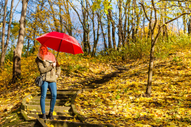 istock Woman walking in park with umbrella 827298156