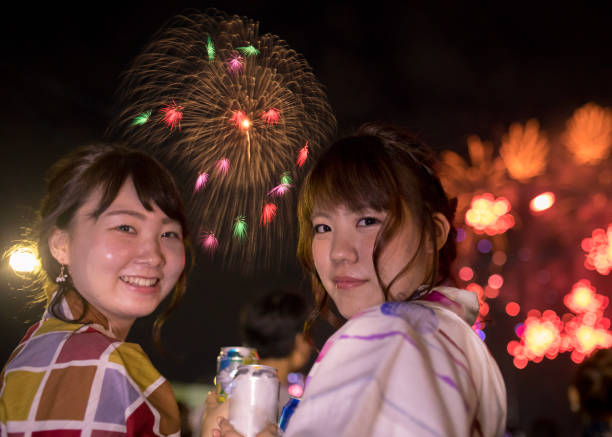 istock Young women in yukata looking over shoulder in fireworks show 827298202