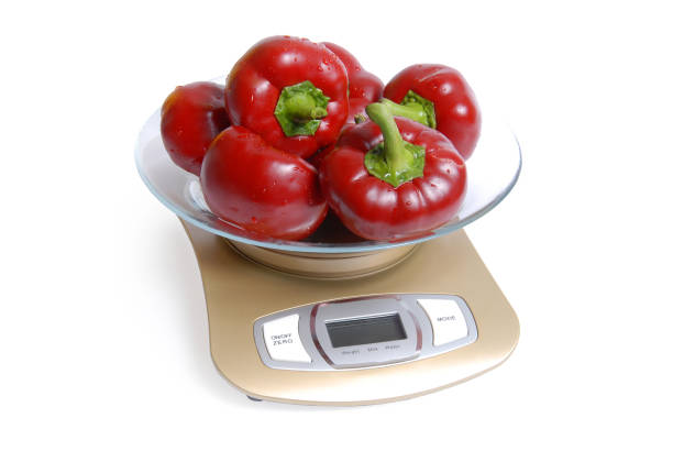 Red sweet peppers on scales on a white background