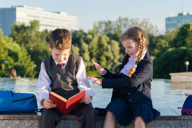 istock Girl in school clothes distracting a student from reading a book 827303108