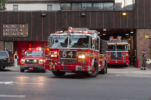 New York - July 13, 2017: Firefighters trucks leaving their fire station (Engine 54, Ladder 4, Battalion 9), to the streets of Manhattan of New York City