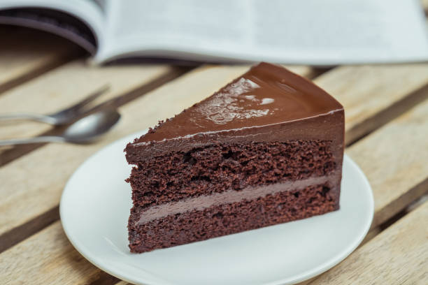 Chocolate cake and book on wooden table