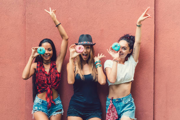 Attractive women making funny faces with colorful donuts
