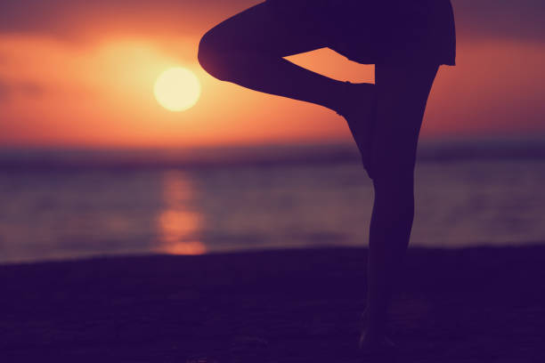 Young woman practicing yoga on the beach.