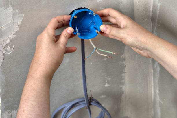 istock Hands electrician electrical box mounted in the wall opening. 827349276