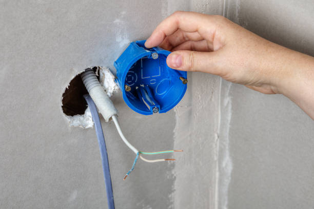 istock Install electrical box in the wall hole, hand close-up. 827349318