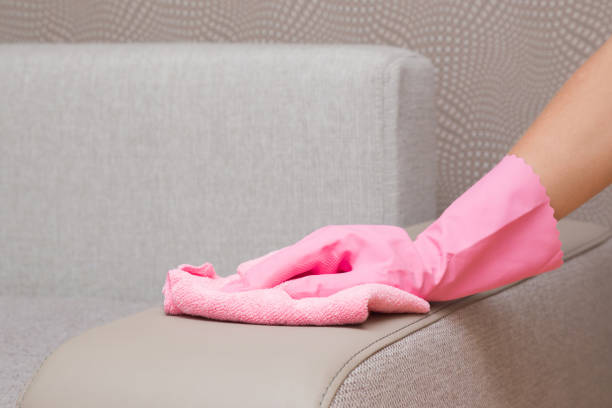 istock Hand in rubber protective glove with microfiber cloth cleaning a textile sofa leather area. Upholstered furniture. Early spring or regular clean up. 827349640