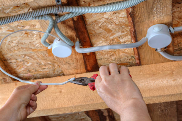 istock Hands of electrician with pliers during working on ceiling wires. 827349656
