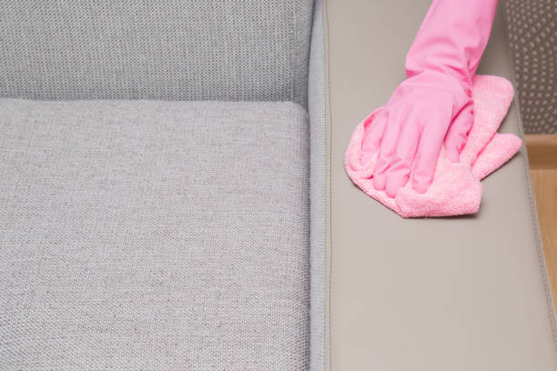 istock Hand in rubber protective glove with microfiber cloth cleaning a textile sofa leather area. Upholstered furniture. Early spring or regular clean up. 827350206
