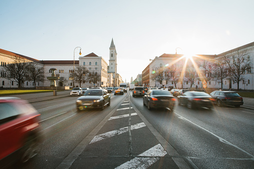 View of the road on the street Leopoldstrasse in Munich, Germany. Fast blurred motion car on sunset background.