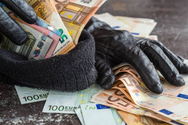 Quick loot in the store. Thief' s hands in black leather gloves stealing a money and putting it in the his hat. Many money. stock photo