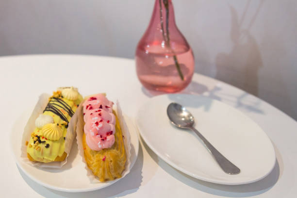 istock Two eclairs with pink cream and yellow cream on a plate 827362314