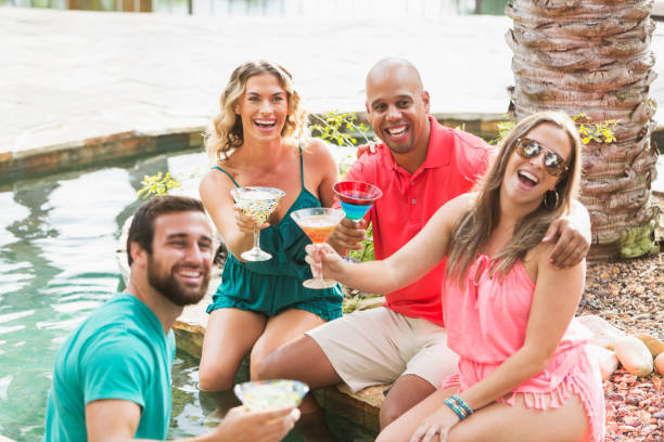 istock Two couples enjoying drinks by resort swimming pool 827364784
