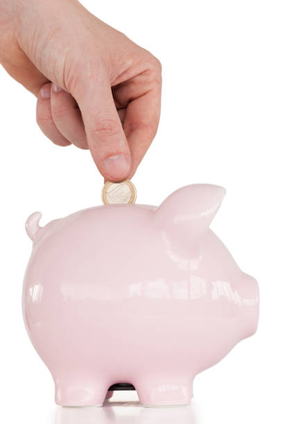 istock Hand inserting a coin in a pink piggy bank 827376126