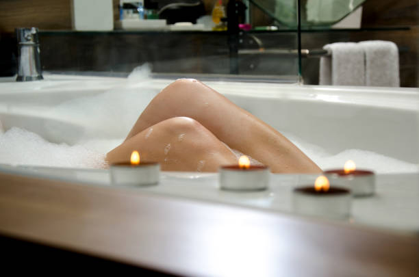 istock Young woman in bubble bath, illuminated candles in foreground 827376546
