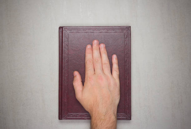 A man's palm on a book, an oath on the bible. Top view from above
