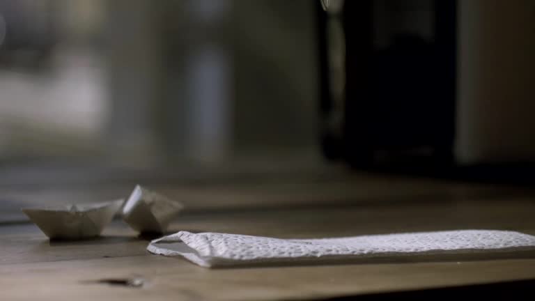 Men hand writing on napkin and holding cup of coffee in another hand.