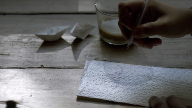 Men hand writing on napkin and holding cup of coffee in another hand.