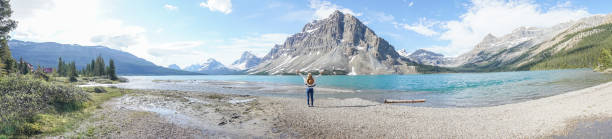 vista panoramica delle braccia della giovane donna distese dal lago di montagna - bow lake foto e immagini stock