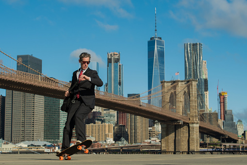 Businessman listening to a podcast while skateboarding to work