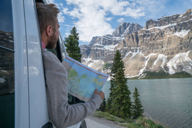 young man looks at road map near mountain lake - bow lake imagens e fotografias de stock