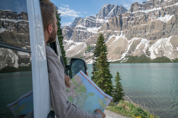istock Young man looks at road map near mountain lake 827401558