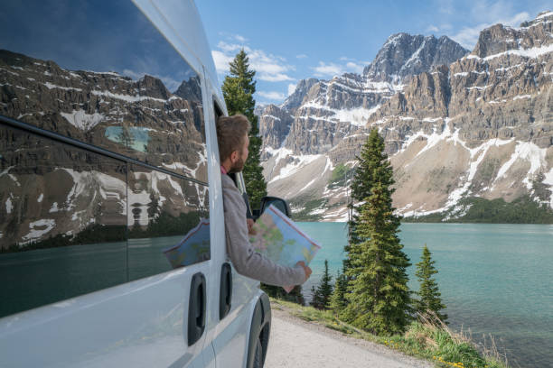 young man looks at road map near mountain lake - bow lake imagens e fotografias de stock