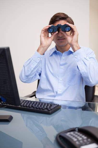 istock Businessman looking through binoculars in his office 827410750