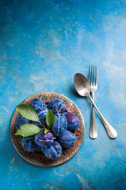istock Plums group with leaves on plate with fork and spoon 827410818