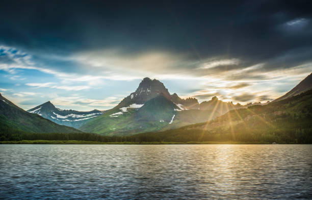 lago swiftcurrent ao amanhecer - alpenglow sunrise sun scenics - fotografias e filmes do acervo