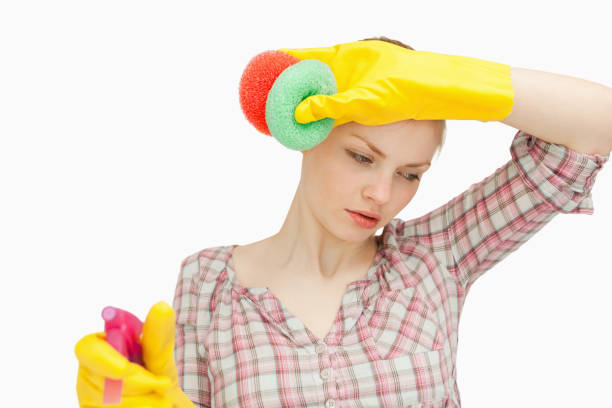 istock Young woman wiping her forehead while holding sponges 827426072