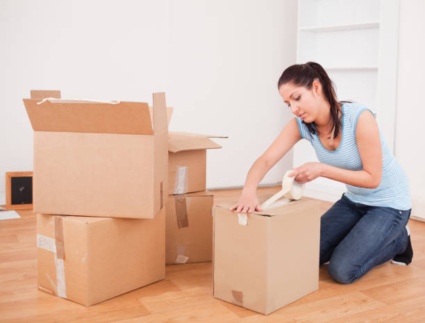 istock Pretty woman taping a box kneeling 827426254