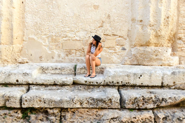 istock Attractive young woman sitting on stone steps 827432058