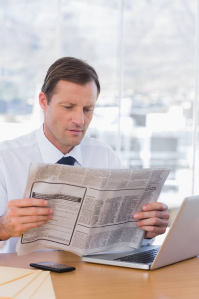 istock Serious businessman reading a newspaper 827434752