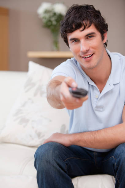 istock Man on the sofa switching on television 827448862
