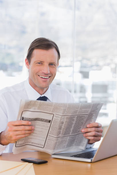 istock Smiling businessman reading a newspaper 827454184