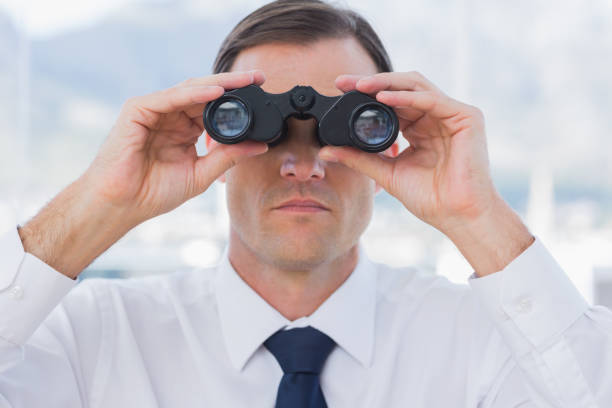 istock Close up of businessman using binoculars 827454334