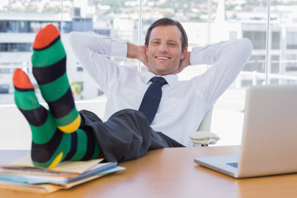 istock Smiling businessman relaxing with feet on his desk 827456924