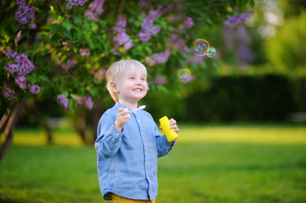 istock Cute little boy blowing soap bubbles in park 827468594