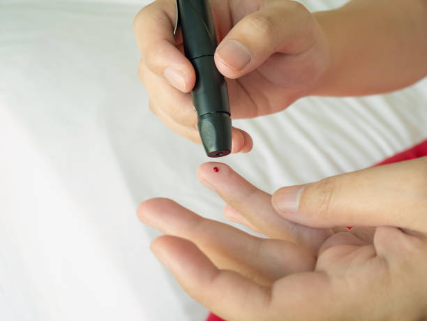 istock woman using lancelet on finger, diabetes test 827468932