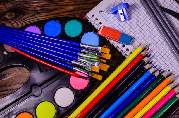istock Set of different school stationeries. Notepad, scissors, pensils, paints, paintbrushes on wooden desk. Back to school. Top view 827472736