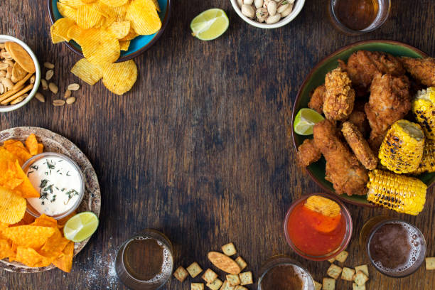 marco de pollo frito, cerveza, salsas, papas fritas, nachos, cacahuates, pistachos y galletas en la mesa de madera - wing spicy chicken wings chicken sauces fotografías e imágenes de stock