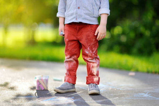 istock Happy little kid boy sitting and drawing with colored chalk on asphalt 827475212