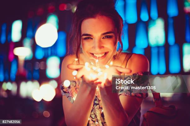 Beautiful Young Woman Smiling And Talking Garlands Of Lights At City Stock Photo - Download Image Now