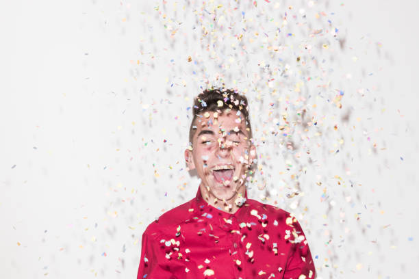 istock one Caucasian teenager, white background studio, smiling laughing, confetti falling, eyes closed, red shirt, head and shoulders shot, 827482406