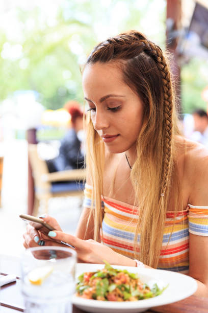 istock Blond woman typing on smart phone in restaurant 827486080