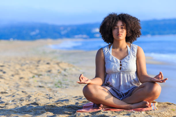 istock African woman sitting on sand and meditating 827486212