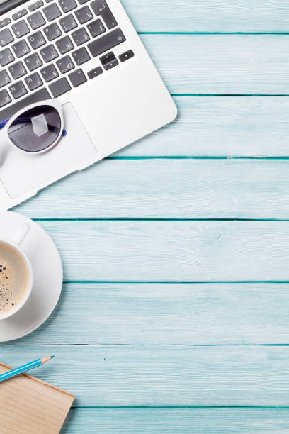 istock Desk table with laptop, coffee and sunglasses 827487144